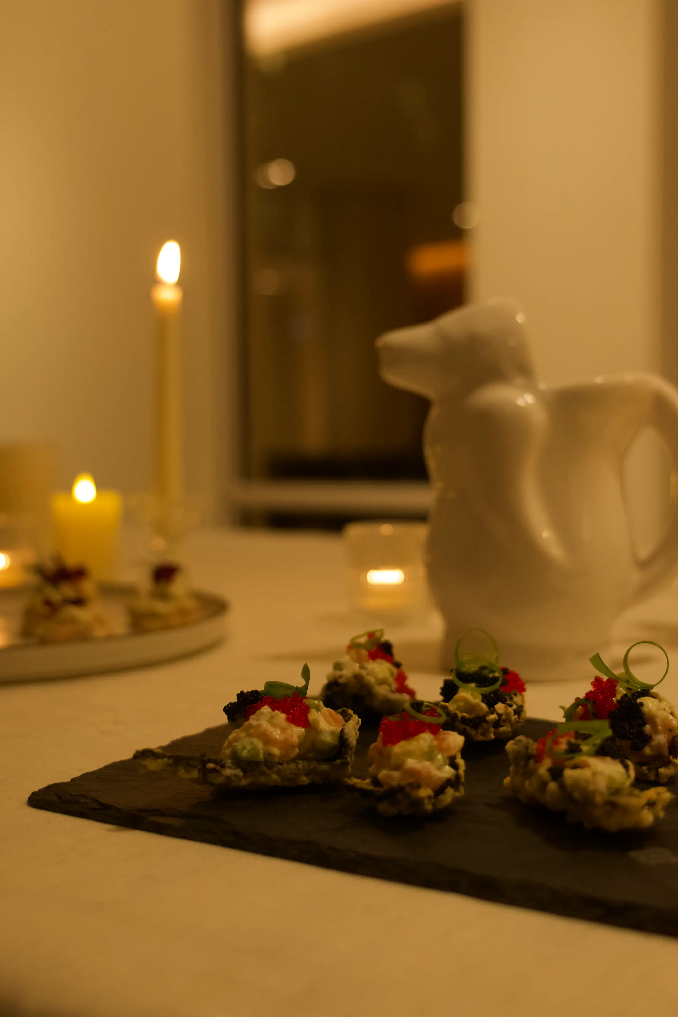 Canapés on a slate, candles behind